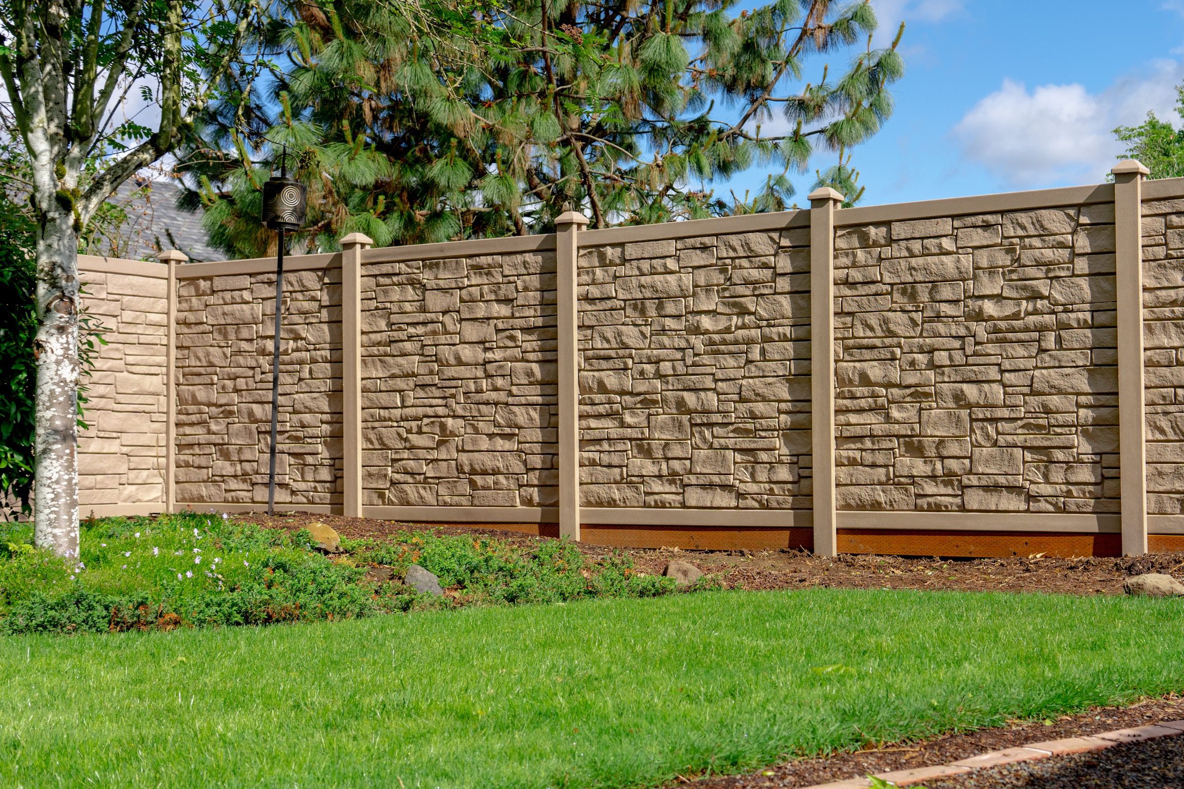 Simulated rock fence with retaining wall