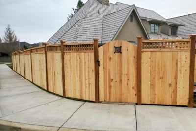 1032 Fencing Cedar Lattice Top A lattice top fence with a gate running along a sidewalk.