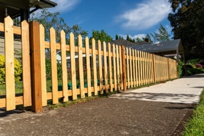 1000 Fencing Cedar Picket A cedar picket fence along a sidewalk.