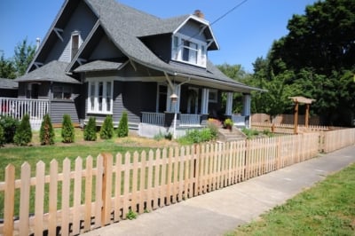 1004 Fencing Cedar Picket A cedar picket fence running along a grassy lawn.