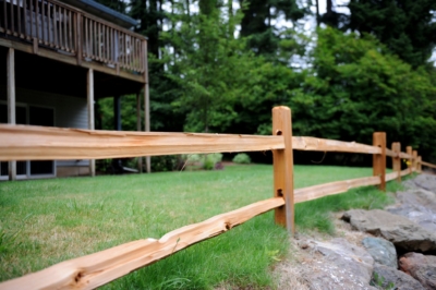 1013 Cedar Split Rail Fencing A close up of cedar split rail fencing with a house in the background.