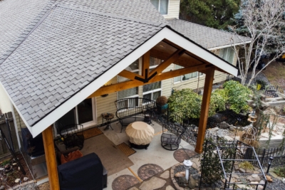 1101 Covers Wood Framed The top of a wooden patio cover, covering a patio filled with furniture.
